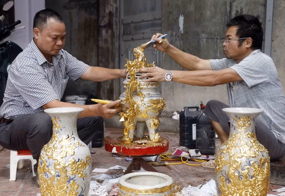 To create a smooth and shiny golden coat for products, gilding craftsmen need to overlay the products with super-thin gold leaves while the paintwork is still wet (Photo: Tran Viet/VNA)