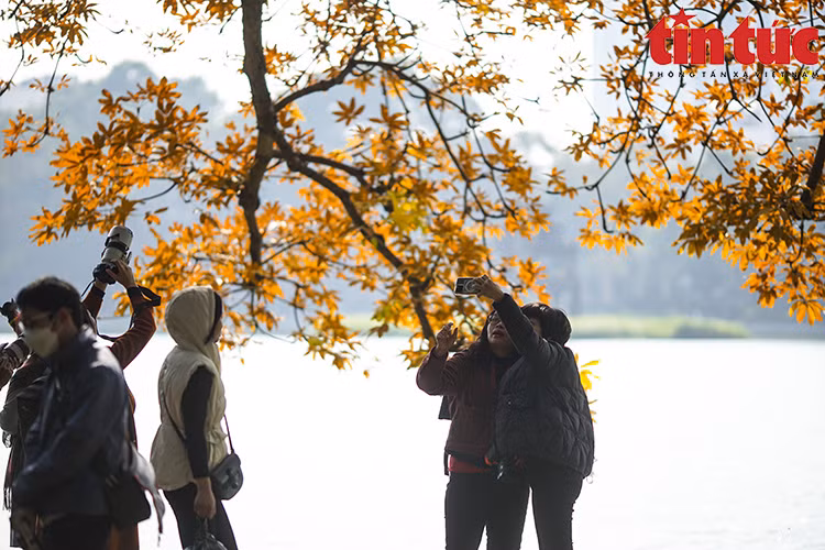 Visitors to Hoan Kiem Lake happily take photographs as mementos of the most romantic moment of the year. (Photo: VNA)