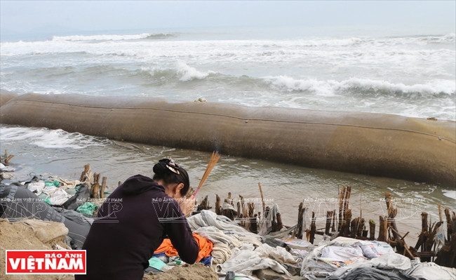 Mai Thi Kiem, who runs a restaurant on Cua Dai beach prays for help to keep her livelihood. (Source: VNA) 