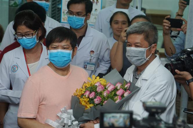 Vietnamese Deputy Minister of Health Nguyen Truong Son gives bouquet to Chinese patient Li Ding to celebrate his recovery (Photo: VNA)