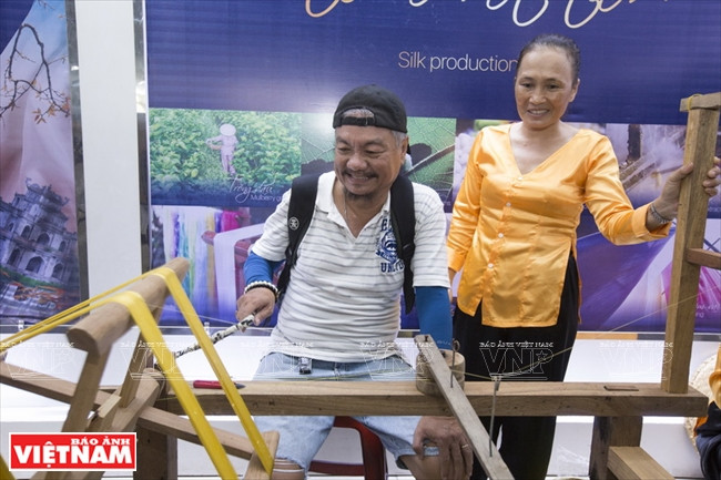 Visitors experience spinning silk process (Photo:VNA)