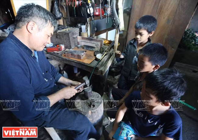 Children in the village watch while To is working (Photo: VNA)