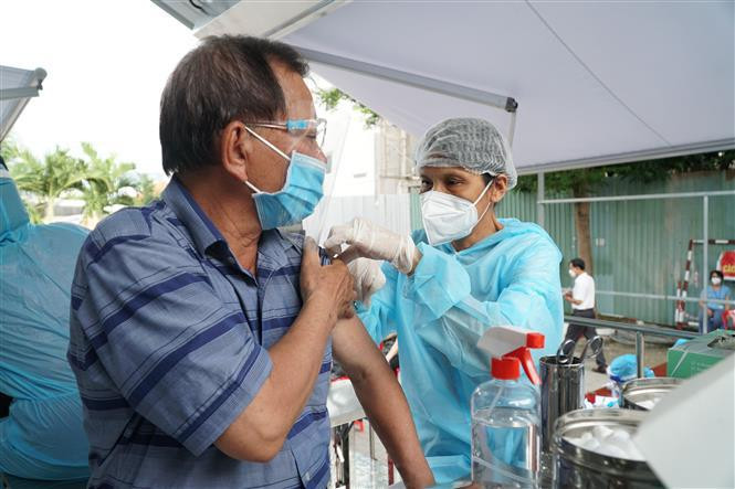 An elderly receives an injection on the mobile vaccination vehicle. (Photo: VNA) 