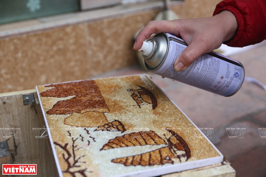 Artist applies a varnish treatment and chemical substance to preserve the colors as well as enhance the aesthetics of the painting. (Photo: VNP/VNA)