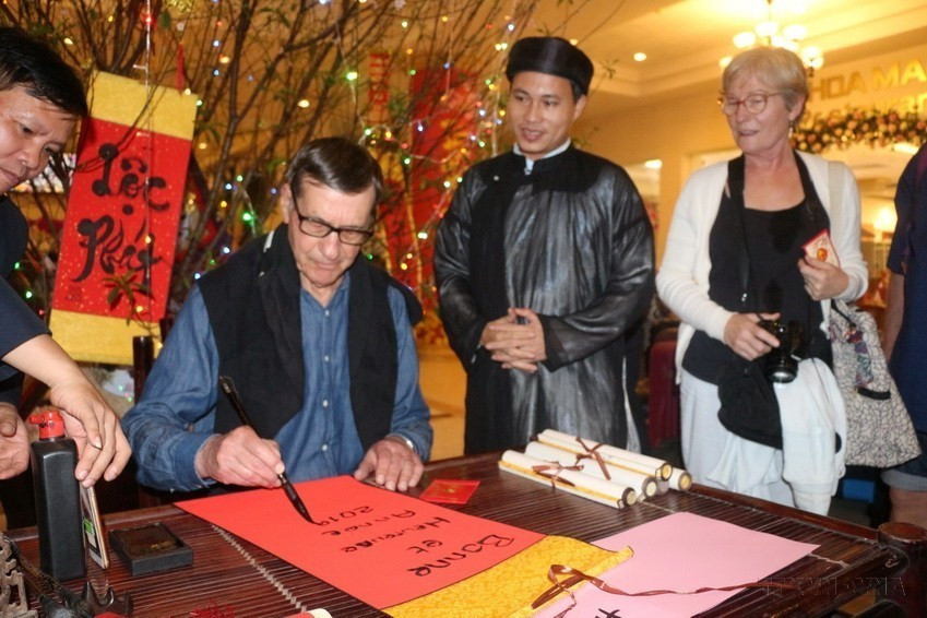 A foreign tourist experiences calligraphy. (Photo: VNA)