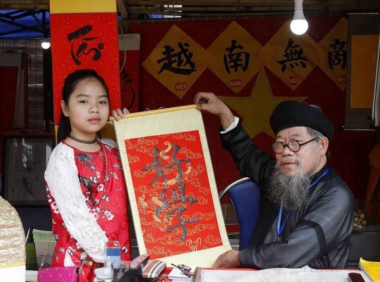 People come to the scholars and tell them about their wishes for the New Year, which will then be written down in Chinese script. People believe that those calligraphic scripts will help turn their wishes into reality. (Photo: VNA)