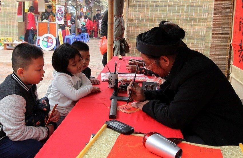 Tet is really a golden chance for children to visit those scholars to ask for parallel sentences which are believed to bring some of the scholars’ erudition and luck to their home. (Photo: VNA)