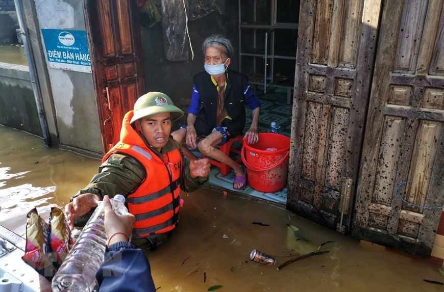 Public security officers wade in flood water to bring relief supplies to isolated households (Photo: VNA)