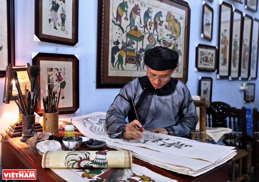  An artisan finalizes a painting with his hand drawing after it is printed. (Photo: VNP/VNA)