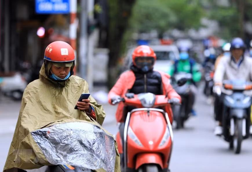 Manual workers wear raincoats to avoid chilly weather (Photo: VNA)