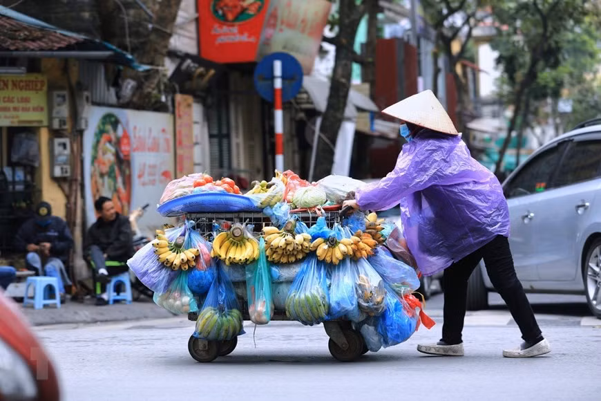 Though it does not rain, some people still put on raincoat to warm up their bodies (Photo: VNA)