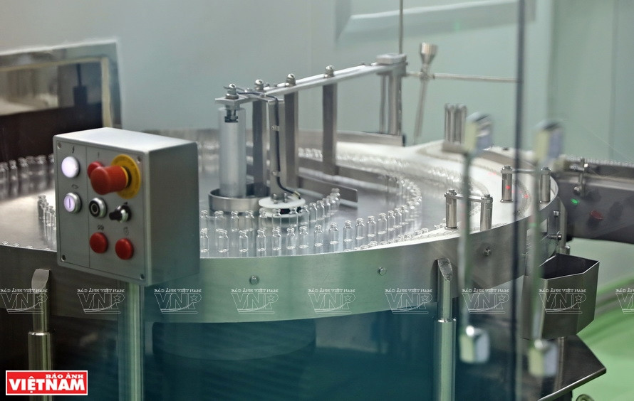 Glass vials for the vaccine are dried, washed and put into a rotating chain to remove all impurities before packaging. (Photo: VNP/VNA)