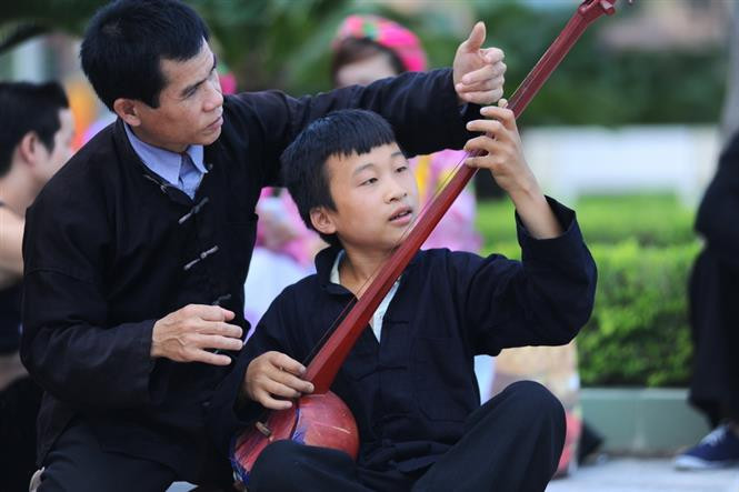 Artisan Hoang Duc Thang (L), in Dang village, Cao Bo commune, Vi Xuyen district, Ha Giang province, teaches a young boy how to use a gourd lute, traditional music instrument accompanying Then singing (Photo: VNA)