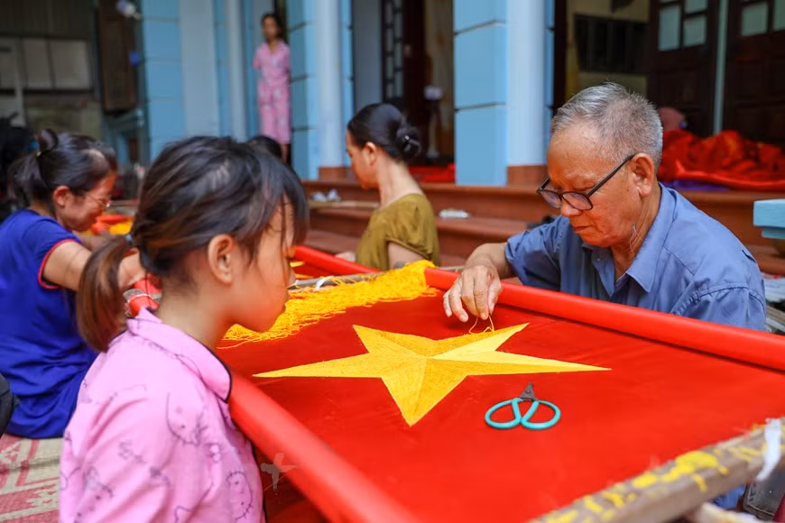 The most important step in making a crafted flag is choosing the right materials. The fabric must be satin purchased from La Khe – a renowned fabric weaving craft village in Hanoi’s Ha Dong outlying district. The satin must be thick, brightly red, and durable. The threads, meanwhile, are bought from Trieu Khuc, another renowned fabric weaving craft village in Hanoi’s outlying Thanh Tri district. Embroidering a flag is a painstaking and time-consuming process that undergoes several steps such as choosing fabrics, measuring fabrics, cutting fabrics, and embroidering the five pointed golden star, among others. Each step requires a lot of efforts and meticulousness from the makers. (Photo: VietnamPlus)