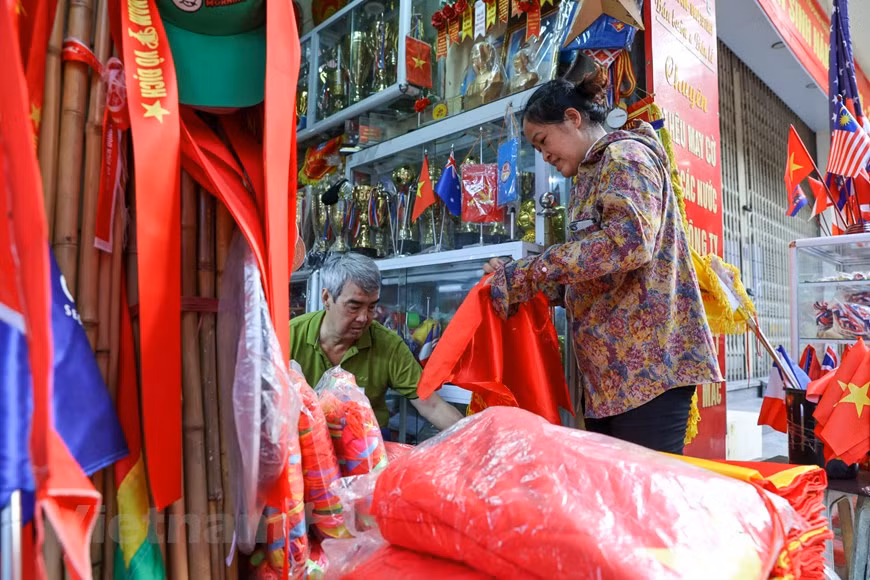 As National Day (September 2) approaches, the workshop of Vuong Thi Nhung’s family becomes busier with non-stop production and delivery. Their products are mostly sent to Hang Bong street in Hanoi’s Hoan Kiem district, which is famous for its long-time tradition of selling flags. “Years ago when my father was still alive before passing away at the age of 104, he used to bicycle flags to our customers on Hang Bong street. Nearly a century old at the time, yet he pedaled dozens of miles every single day. He was among the first to bring the flag embroidery craft to Tu Van,” Nhung proudly said. (Photo: VietnamPlus)