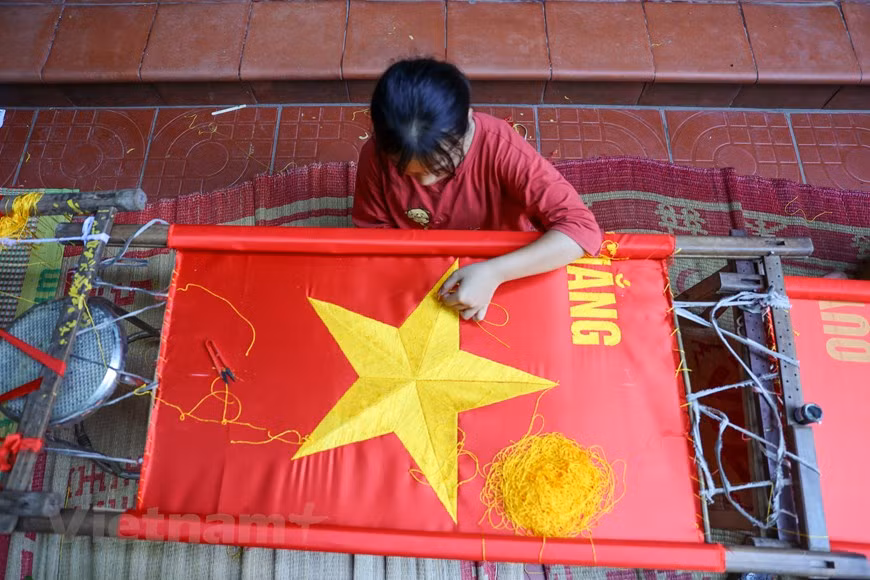 According to veteran embroiderer Vuong Thi Nhung, wages paid for embroiderers are higher than for sewers by between 200,000 VND and 250,000 VND (8.63 USD – 10.78 USD) per day. Sewing is much simpler than embroidering a flag. In a day, hundreds of flags can be made using sewing machines, while it takes weeks for embroiderers to achieve the same volume. Embroidering a flag is a painstaking and time-consuming process that undergoes several steps such as choosing fabrics, measuring fabrics, cutting fabrics, and embroidering the five-pointed golden star, among others. Each step requires a lot of efforts and meticulousness from the makers. (Photo: VietnamPlus)