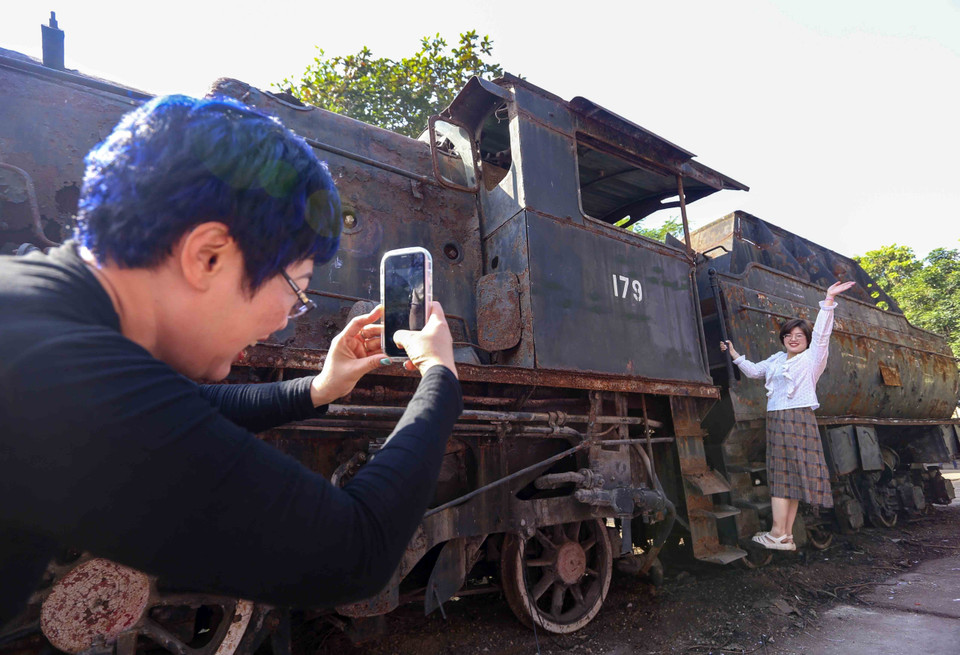 Visitors pose for photos at the Tu Luc steam locomotive, displayed within the framework of the Hanoi Creative Design Festival 2023. (Photo: VNA)