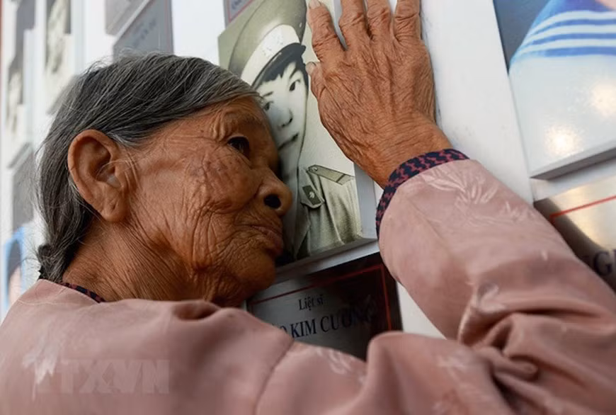 Mrs. Ha Thi Lien from Can Loc district, Ha Tinh province, mother of martyr Dao Kim Cuong, kisses on her son’s portrait at the memorial to Gac Ma soldiers. (Photo: Published by VNA)