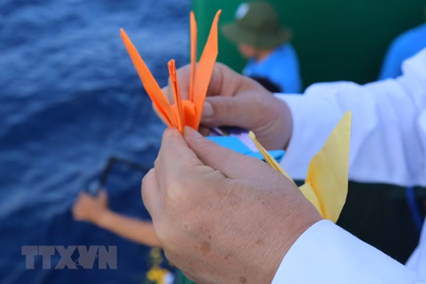 Paper cranes are dropped into the sea by officers and soldiers of Truong Sa 571 ship to commemorate the martyrs who sacrificed their lives for safeguarding the nation’s sea and islands. (Photo: VNA) 