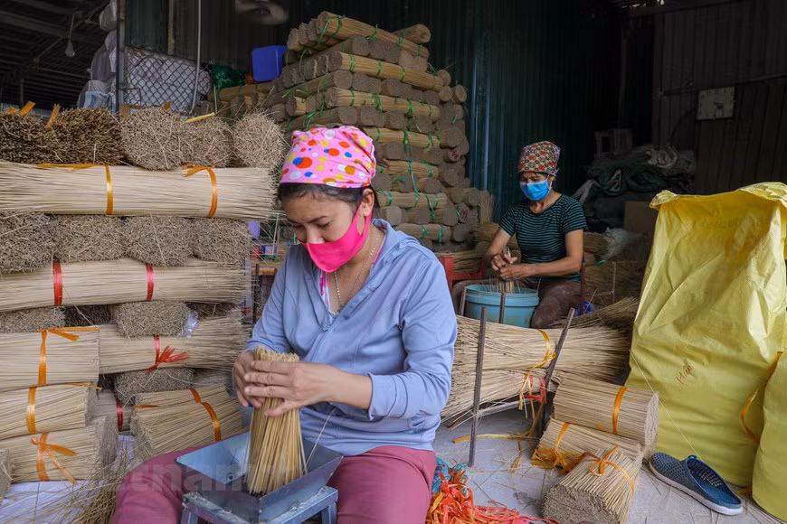 Located just more than 30 kilometres from downtown Hanoi, the village in Quang Phu Cau commune still retains a number of traditional features of a village in the northern region of Vietnam. To produce incense, local craftsmen firstly dry and split bamboos into thin sticks. Nowadays, machines have been applied to make the work easier, thus saving time and effort. After that, they will classify the bamboo sticks into two types: the bamboo sticks with better quality will be dyed to make joss sticks while the one with lower quality will be recycled. The dyed sticks will then be tied into bunches and laid on the ground for drying, creating a beautiful landscape. (Photo: VietnamPlus)