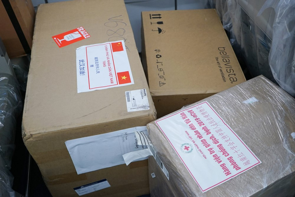 The first known infections from the SARS-CoV-2 strain were discovered in Wuhan, China. The original source of viral transmission to humans remains unclear, as does whether the strain became pathogenic before or after the spillover event. Because many of the first individuals found to be infected by the virus were workers at the Huanan Seafood Market, it has been suggested that the strain might have originated from the market. In January 2020, the World Health Organisation recommended "2019 novel coronavirus" (2019-nCov) as the provisional name for the virus. In the photo: Medical equipment and supplies of the Vietnamese Government and people presented to Chinese people to help them fight against the COVID-19 pandemic are also brought on this flight. (Photo: Vietnam+)