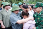 Prime Minister Pham Minh Chinh consoles a family whose member dies in recent floods in Xa Dung commune. (Photo: VNA)