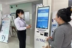 Long An General Hospital's staff guides a local resident on how to use the self-service medical check-in kiosk. (Photo: VNA)