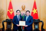 Politburo member, President of the Ho Chi Minh National Academy of Politics (HCMA) and Chairman of the Central Theory Council Nguyen Xuan Thang (R) presents the HCMA's insignia "For the cause of political theory education and training" to Choi Joo Ho, General Director of Samsung Vietnam. (Photo: VNA)