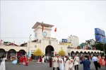 Tourists pose for photos in front of Ben Thanh Market, Ho Chi Minh City. (Photo: VNA)