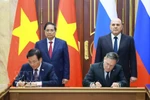 Vietnamese PM Pham Minh Chinh (standing, left) and his Russian counterpart Mikhail Mishustin (standing, right) witness the signing of the agreement between the two governments on cooperation in building a nuclear power plant on the territory of Vietnam. (Photo: VNA)