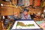 An artisan embroiders a painting at the exhibition area. (Photo: VNA)