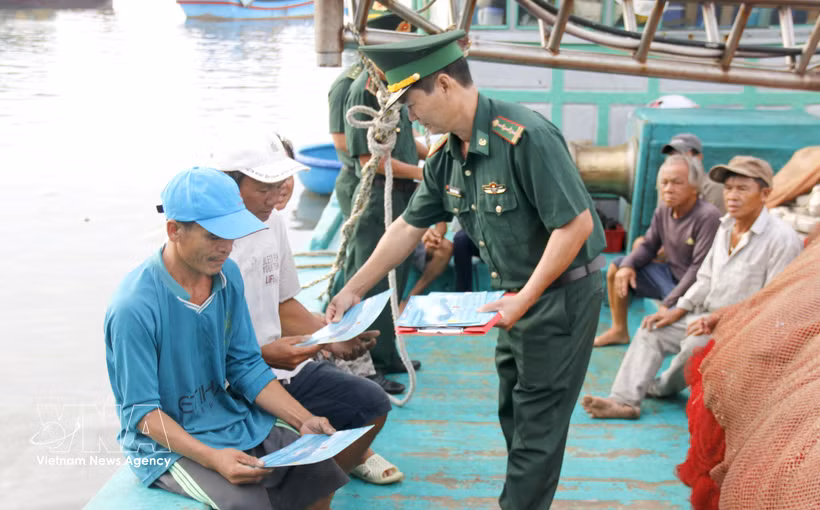 An officer of the Thanh Hai Border Guard Station, Lam Dong province, distributes leaflets on anti-IUU fishing regulations to fishermen. (Photo: VNA)