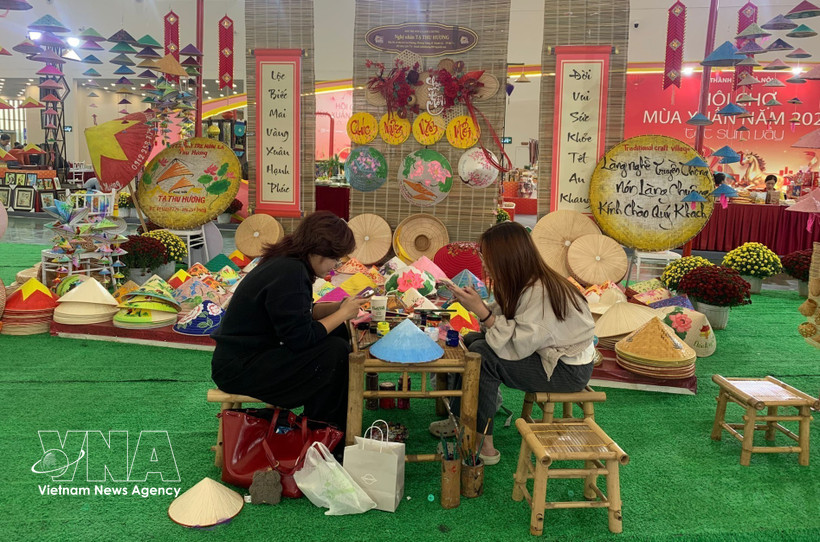 Young visitors come to enjoy their time at the booth of Chuong conical hat making village at the Glorious Spring Fair 2026 in Hanoi (Photo: VNA)