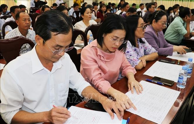 Delegates review brief biographical profiles of candidates for the 16th National Assembly at a consultative conference. (Photo: VNA)