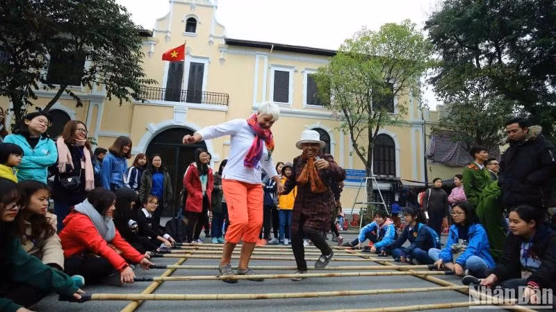 Foreign tourists enjoy a folk cultural activity in Hanoi (Photo: Nhan dan Newspaper)