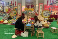 Young visitors come to enjoy their time at the booth of Chuong conical hat making village at the Glorious Spring Fair 2026 in Hanoi (Photo: VNA)