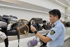 Tran Viet Hung from the Department of Domestic Market Management and Development examines handbags. (Photo: VNA)