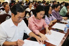 Delegates review brief biographical profiles of candidates for the 16th National Assembly at a consultative conference. (Photo: VNA)