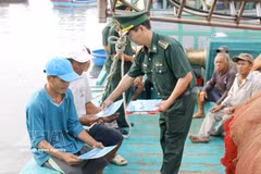 An officer of the Thanh Hai Border Guard Station, Lam Dong province, distributes leaflets on anti-IUU fishing regulations to fishermen. (Photo: VNA)