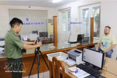 An immigration officer takes a photo of a foreigner as part of procedures for providing a Level-2 electronic identification account. (Photo: VNA)