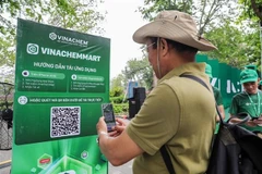 A man scans the QR code of e-commerce platform VinachemMart at the launch on May 10. (Photo: VNA)