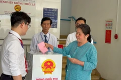 A voter under treatment at the Ho Chi Minh City Hospital of Dermato-Venereology drops her ballot into a mobile ballot box on March 15. (Photo: VNA)