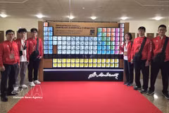 The Vietnamese delegation poses for a photo beside the Mendeleev periodic table before the opening ceremony. (Photo: VNA)