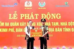 Lieutenant General Pham The Tung (R), member of the Party Central Public Security Committee and Deputy Minister of Public Security, presents the token for funding to eliminate 500 makeshift and dilapidated houses in Dak Nong province. (Photo: VNA) 