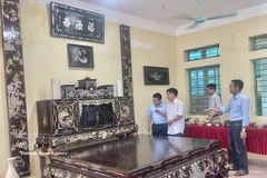 Artisan Vu Van Vinh from Chuyen My commune introduces to visitors a set of mother of pearl inlaid lacquer furniture including a platform bed, tea cabinet, and lacquered horizontal boards and parallel sentences made by his family, worth more than 3 billion VND. (Photo: VNA) 