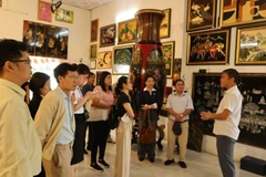 Visitors are introduced to the history of lacquer paintings at the Dinh Hoa lacquerware workshop. (Photo: VietnamPlus)