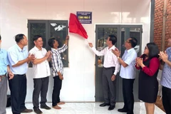 Secretary of the Bu Dang district Party Committee and Head of the Steering Committee for Eliminating Dilapidated Housing, Vu Luong (fourth from right), performs the ribbon-cutting ceremony to hand over a new house to a disadvantaged household. (Photo: VNA)