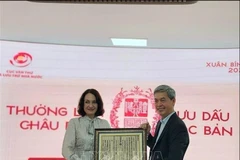 Director of the State Records and Archives Department of Vietnam Dang Thanh Tung presents Elena Bezdetko, spouse of the Russian Ambassador to Vietnam, with a woodblock print of Vietnam’s national title (Photo: VNA) 