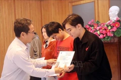 Pham Minh Tuan, Vice Chairman of Ho Chi Minh City’s Vietnam Fatherland Front Committee, presents health insurance cards to impoverished students. (Photo: VNA)