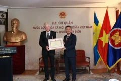 Ambassador Tran Van Tuan (R) presents the âFor the Cause of Culture, Sports and Tourismâ insignia to Swedish filmmaker Bo ĂhlĂ©n. (Source: Embassy of Vietnam in Sweden)